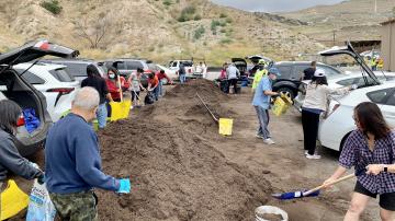 People shoveling compost into buckets.