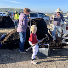 Little boy with family helping shovel compost into bucket.