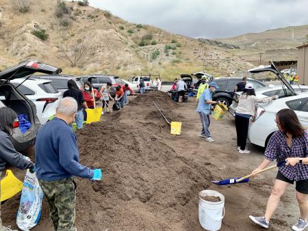 People shoveling compost into buckets.