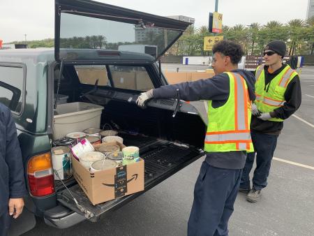 Two staff pulling large tv out of trunk