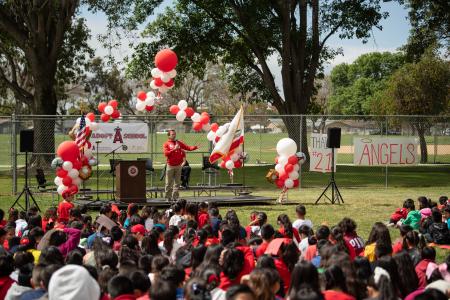 Man on stage in front of a crowd of students.