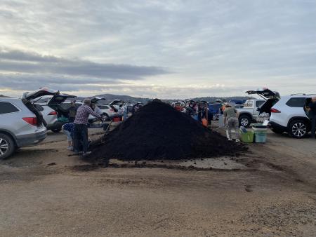 Residents parked in front of a compost windrow, filling their cars with compost.