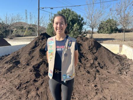 Photo of Bella/Girl Scout in front of compost pile